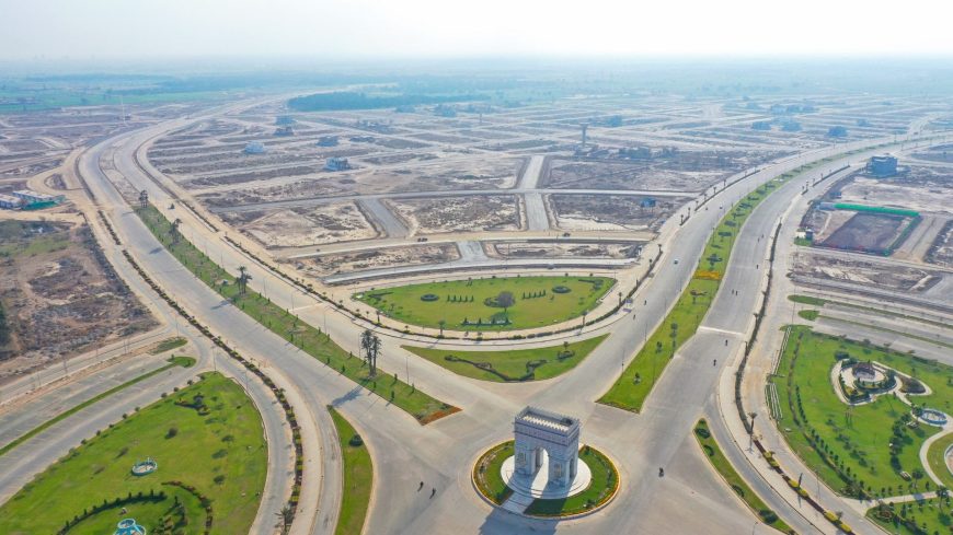 Aerial view of DHA Multan in the shining morning light, showcasing well-organized roads, residential plots, and lush greenery under a bright, clear sky.