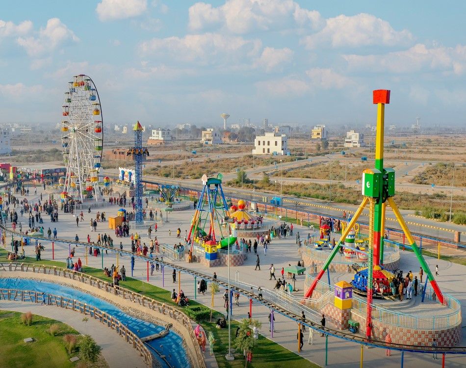 A scenic view of Kashmir Park in DHA Multan, featuring lush green lawns, vibrant flower beds, walking trails, and families enjoying the serene environment.